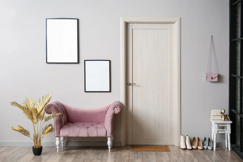 Interior of light hall with armchair, frames and wooden door